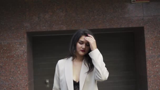 Stijlvolle brunette in een beha en jas verleidelijk loopt poseren op de parkeerplaats — Stockvideo