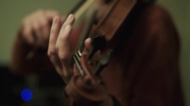 Kadın sanatçı kulaklık kullanarak kemanla enstrümantal melodiyi prova ediyor.