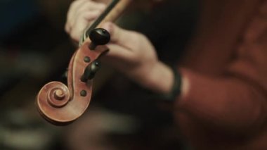 Kadın kemancının enstrümantal melodiyi kemanla prova edişine yakından bakın.