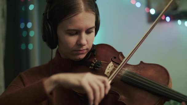 Giovane donna che prova la melodia strumentale con violino usando le cuffie — Video Stock