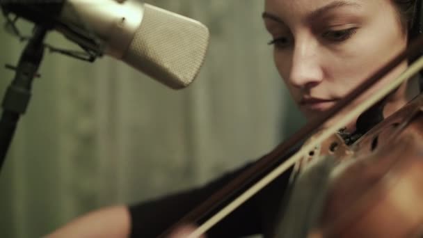Ženská houslistka nacvičuje se sluchátky u mikrofonu — Stock video