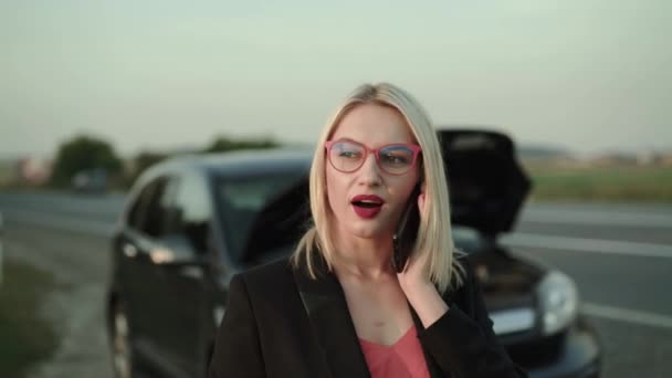 Красивая блондинка получает звонок и говорит рядом со сломанной машиной на террасе — стоковое видео