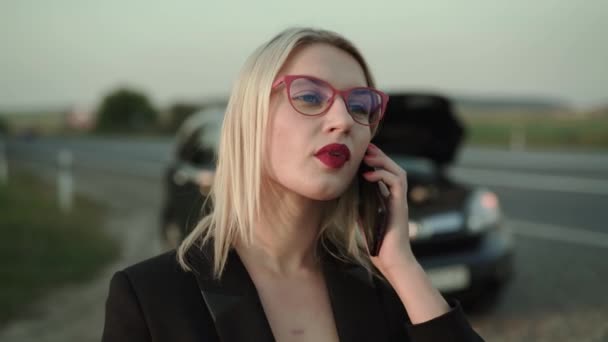 Красивая блондинка получает звонок и с радостью разговаривает рядом со сломанной машиной — стоковое видео