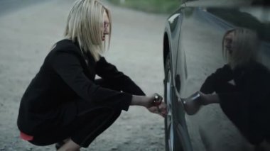 Zarif bayan tekerleği bozuk arabayla söker ve anahtarı yere atar.