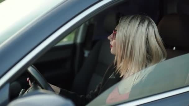 Красива дама сидить на передньому сидінні автомобіля, крутиться і посміхається на камеру — стокове відео