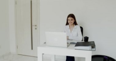 Mutlu ofis kızı iş yerindeki bilgisayara sevinir, ellerini kaldırır ve güler.