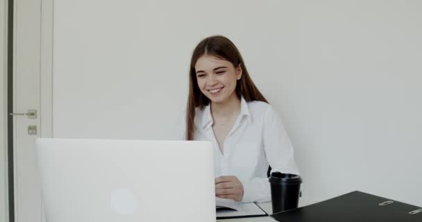 Jovem menina do escritório conversando com sorriso em um laptop no local de trabalho — Vídeo de Stock