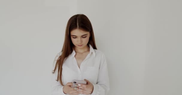 Портрет молодої дівчини, яка дивиться на мобільний телефон і друкує на ньому — стокове відео