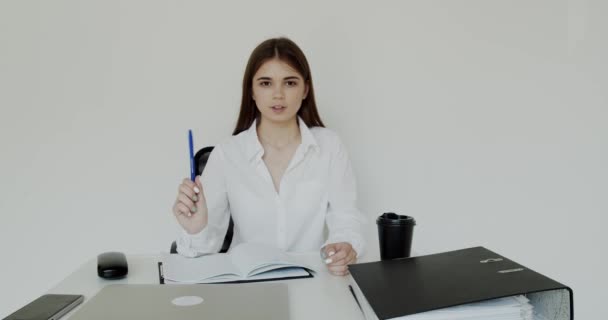 Menina escritório feliz falando com sorriso e caneta na mão para câmera no local de trabalho — Vídeo de Stock