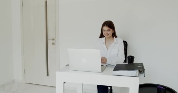 Happy office meisje glimlachen wanneer zitten aan tafel en kijken op laptop — Stockvideo