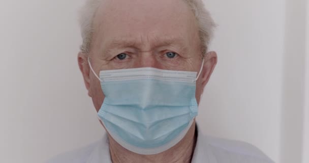 Triste homme âgé dans un masque médical avec le virus soupçonné de regarder dans la caméra — Video