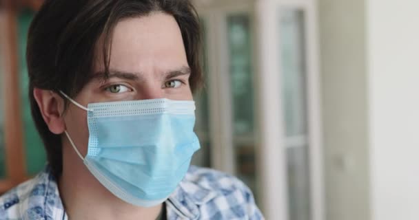 Portrait de jeune homme abaisse masque médical et regarde attentivement la caméra — Video