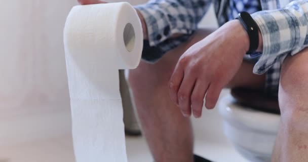 Man houdt wc-papier, klemt vuist in pijn bij het lijden constipatie — Stockvideo