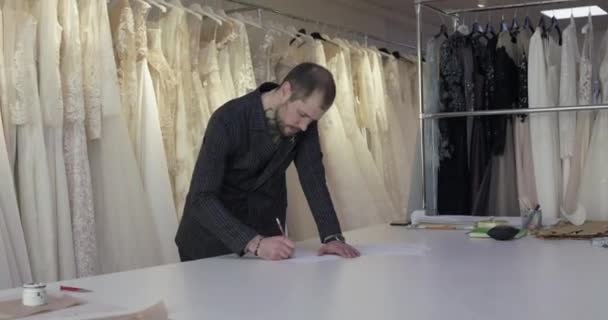 Man ontwerper tekent schets in jurk atelier — Stockvideo