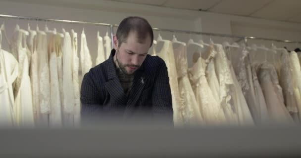 Portret van mannelijke ontwerper tekent schets op een bureau in kledingatelier — Stockvideo