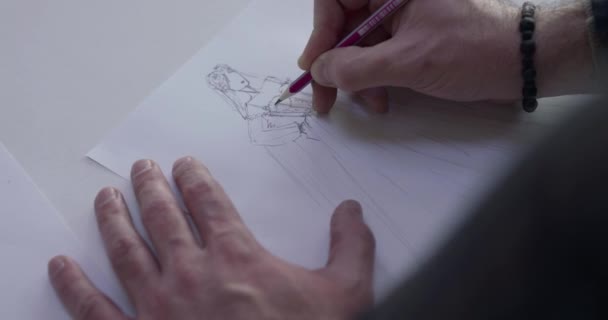 Bovenaanzicht van mannelijke ontwerpers hand tekent een trouwjurk schets op een bureau — Stockvideo