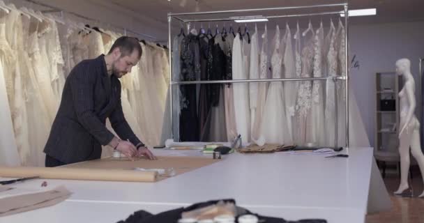 Penjahit menggambar kurva pada kain pada desktop di atelier gaun — Stok Video