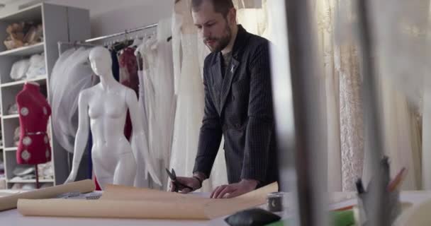 Портной резки тканей кривой на рабочем столе в платье ателье — стоковое видео