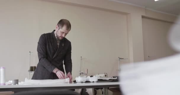 Krawiec przywiązuje guziki do rękawa sukienki na pulpicie w atelier — Wideo stockowe