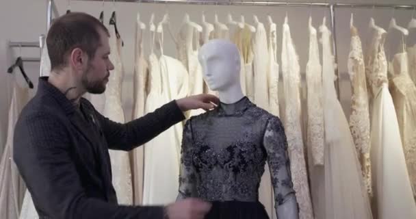 Σχεδιαστής μόδας δοκιμάζει ένα ραμμένο βραδινό φόρεμα σε μια κούκλα στο ατελιέ — Αρχείο Βίντεο