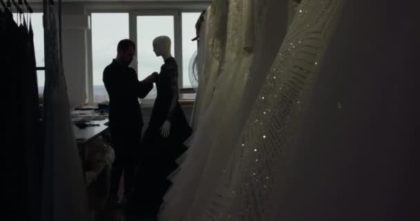 Silhouette Ansicht des Schneiders schmückt ein genähtes Abendkleid auf Schaufensterpuppe im Atelier — Stockvideo