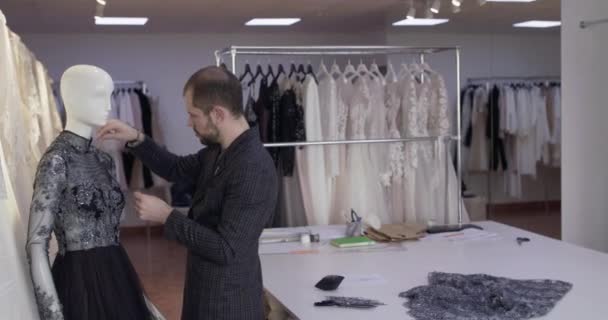 テーラーはアトリエでマネキンに縫い付けられたイブニングドレスのピンで対策を修正します。 — ストック動画