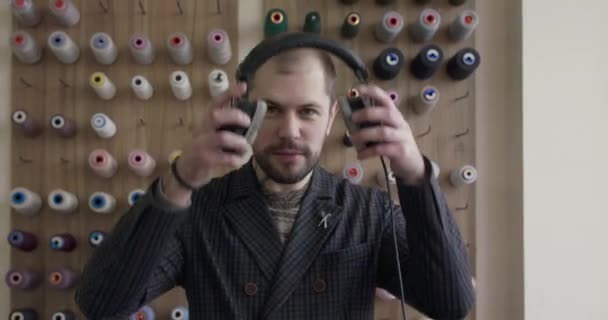 Hombre poniéndose los auriculares y asintiendo con la cabeza con el disfrute de la cámara en el taller — Vídeo de stock