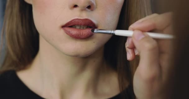 Primer plano de labios de chica con maquillaje desnudo perfecto. Maquillaje proceso de pintura de labios con un lápiz labial para hermosa modelo femenina joven — Vídeos de Stock