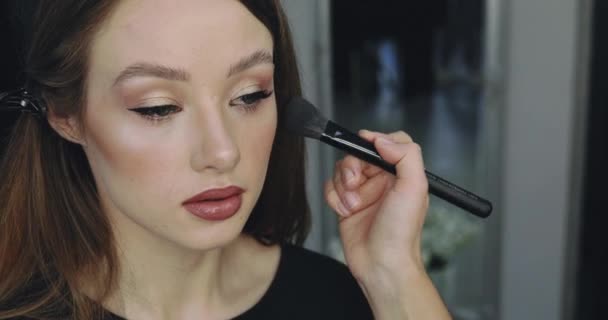 Närbild av flicka med perfekt naken make-up och make-up artist. Make-up process ansikte kontur för vackra unga kvinnliga modellen — Stockvideo