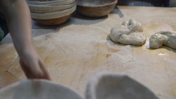 Τα χέρια των αρτοποιών σχηματίζουν ζύμη σε ένα τραπέζι μετά από αυτοματοποιημένο εξοπλισμό για το ψήσιμο ψωμιού — Αρχείο Βίντεο