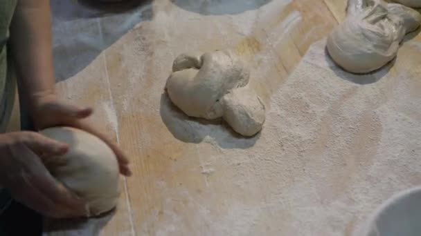 De handen van de bakkers kneden vormen van deeg voor brood bakken op tafel — Stockvideo