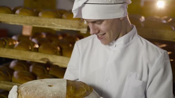 Feliz panadero regocijándose y mostrando gran hogaza redonda de pan con imagen de sonrisa — Vídeos de Stock