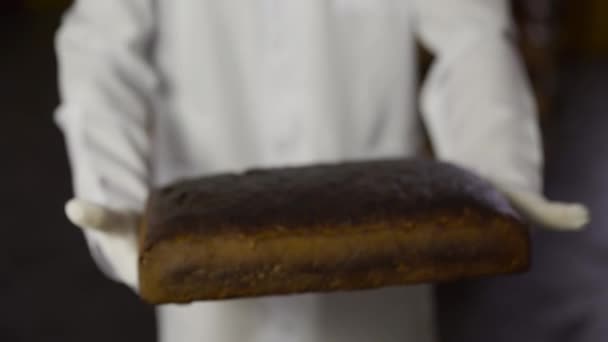 Κοντινή άποψη ενός φούρναρη με στολή παρουσιάζει φρεσκοψημένο ψωμί στην κάμερα — Αρχείο Βίντεο