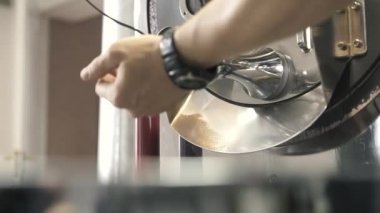 Kişi, makineden kaseye düşen fasulyeleri açar.