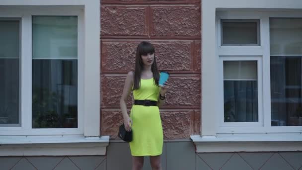 Açık yeşil elbiseli şık genç bayan sokakta bardakta içki içiyor. — Stok video