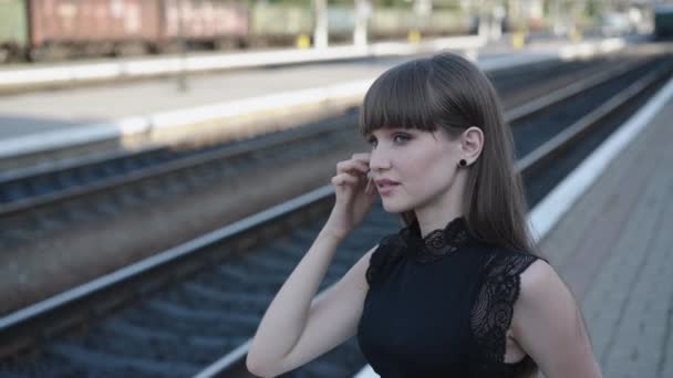 Красива кокетка в чорно-білій сукні з посмішкою на залізниці — стокове відео