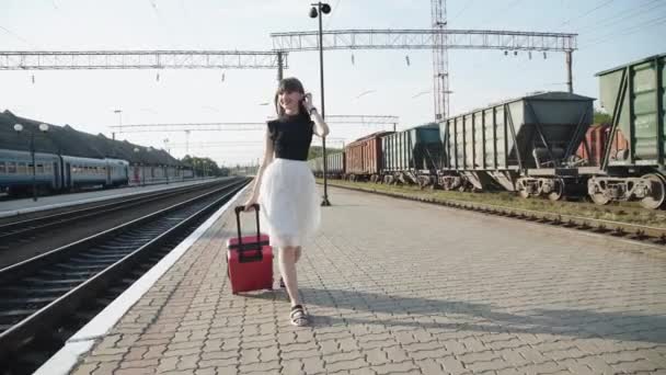 Happy lady va con la maleta y posa con el vestido en la plataforma ferroviaria — Vídeo de stock