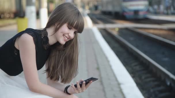 Glad ung flicka talar på mobiltelefon på järnvägsplattform — Stockvideo