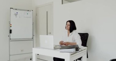 Öğretmen ofisteki bir dizüstü bilgisayarda çevrimiçi bir ders veriyor.