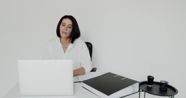 Kvindelig lærer udfører en online forelæsning på en bærbar computer om baggrunden i kontoret – Stock-video