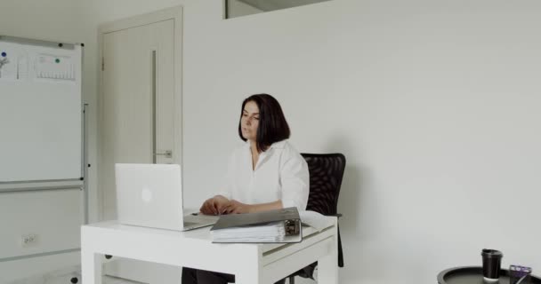 Kvindelig lærer udfører en online forelæsning på en bærbar computer på kontoret – Stock-video