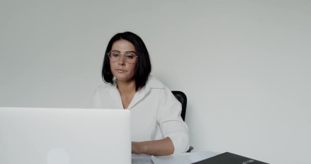 Kvinnlig föreläsare i glasögon chattar på en bärbar dator under distansutbildning på kontoret — Stockvideo