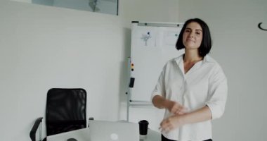 Kendine güvenen bayan öğretmen el ele tutuşup ofiste kameraya gülümsüyor.