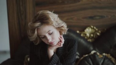 Lüks koltukta oturan, akıllı telefondan yazan ve yan odaya bakan bir kadın.