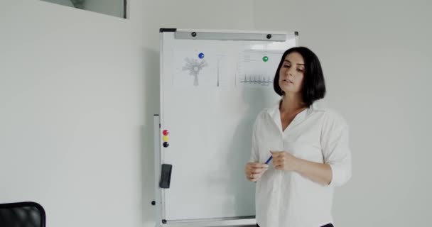Falante feminino realiza palestra no escritório, demonstra tópico no quadro branco — Vídeo de Stock