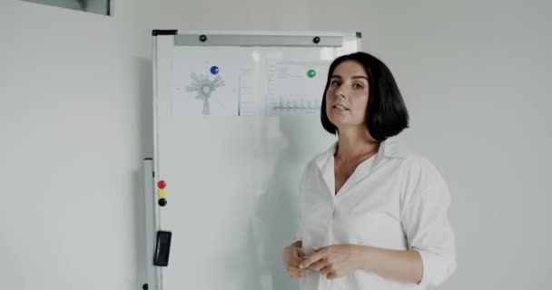 Referentin hält Vortrag vor Kamera am Whiteboard im Büro — Stockvideo