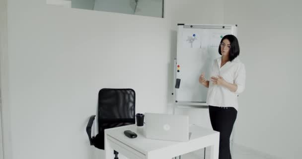 Lehrerin erklärt Thema am Whiteboard mit Gesten vor Laptop — Stockvideo