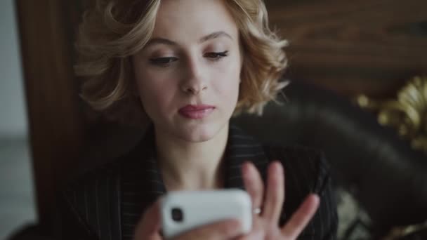 Портрет вдумчивой деловой леди, печатающей на смартфоне в роскошной квартире — стоковое видео