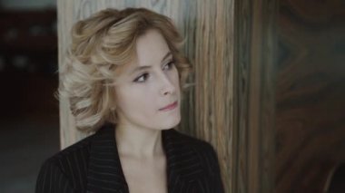 Duvara yaslanmış şık bir kadının portresi, yana bakıyor ve içeride düşünüyor.