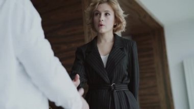 Erkek ortaklar el sıkışıyor ve kameraya bakıyor.